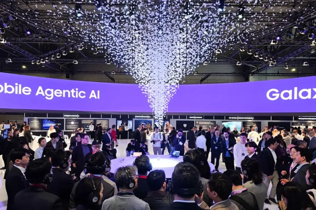 Samsung Galaxy AI se expande en el ecosistema en MWC 2026 Samsung Electronics presentó en el Mobile World Congress (MWC) 2026 de Barcelona una visión ampliada del ecosistema Galaxy centrado en Galaxy AI. Durante el MWC, del 2 al 5 de marzo, Samsung mostró cómo la IA móvil anticipa necesidades y transforma la vida cotidiana. Además, el booth de 1.745 m² en Fira Gran Via atrajo multitudes con demos interactivas. Samsung Galaxy AI se expande en el ecosistema en MWC 2026 Galaxy S26: IA agentiva en smartphones Por una parte, la serie Galaxy S26 ofrece capacidades intuitivas de Galaxy AI respaldadas por hardware avanzado. Por ejemplo, Privacy Display permite activar privacidad en apps específicas sin protectores adicionales. Además, Super Steady con Horizontal Lock estabiliza videos en movimientos laterales o rotaciones de 360 grados. Por otro lado, Photo Assist permite editar fotos con prompts de texto simples. Estas funciones generan reacciones entusiastas entre visitantes. Como resultado, el booth resalta cómo la IA agentiva entiende rutinas y entrega asistencia proactiva . Innovaciones en accesorios y form factors En paralelo, Galaxy Buds4 Pro introduce audio Hi-Fi de 24-bit/96kHz con sistema de dos vías para graves profundos y agudos claros. Super Clear Call usa seis micrófonos para filtrar ruido ambiental en llamadas. Además, Galaxy AI optimiza sonido según la forma del oído con ANC adaptativo. Por una parte, Galaxy XR demuestra interacciones multimodales con voz, mirada y gestos vía Gemini. Por otro lado, Galaxy Z TriFold ofrece pantalla de 10 pulgadas con multi-ventana para tres apps simultáneas. Finalmente, estas innovaciones equilibran productividad y portabilidad. Infraestructura y sostenibilidad con IA Samsung mostró expansión de IA en manufactura con fábricas autónomas para mayor eficiencia. En salud, la visión Connected Care integra Samsung Health con servicios médicos tras adquirir Xealth. Por otra parte, Knox Vault y Knox Matrix protegen datos en el ecosistema Galaxy . Un representante de Samsung destacó que Galaxy AI redefine la interacción móvil al anticipar intenciones y escalar a industrias como retail y marítima. Esta visión une innovación con confianza en seguridad. Samsung mantiene liderazgo global en móviles con tecnologías como displays, cámaras e IA. En Latinoamérica, fortalece presencia vía portafolio Galaxy, atendiendo a millones de usuarios en transformación digital. Samsung Galaxy AI se expande en el ecosistema en MWC 2026. Palabras clave sugeridas: Galaxy AI MWC 2026, ecosistema Galaxy AI, Galaxy S26 IA agentiva, Galaxy Buds4 Pro audio HiFi, Galaxy XR multimodal, Galaxy Z TriFold productividad, IA Samsung,